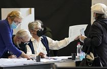 A voter is passed a ballot at a polling station for early voting in Ljubljana on 21 April 2022