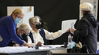A voter is passed a ballot at a polling station for early voting in Ljubljana on 21 April 2022