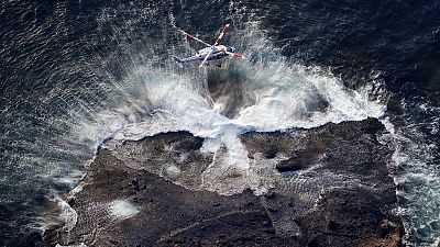 A rescuer is lifted in a search operation for missing passengers and crew members of a sunken tour boat, off Shiretoko Peninsula in northern Japan, on 24 April 2022