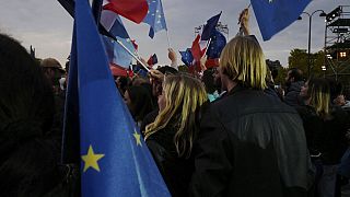 Υποστηρικτές του Εμανουέλ Μακρόν πανηγυρίζουν την επανεκλογή του στο Παρίσι κρατώντας γαλλικές και σημαίες της ΕΕ