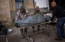 متطوعان أمريكيان ويد هيلتون وداريل لوفليس  يساعدان في نقل جثمان نحو المشرحة المركزية في بوتشا، بضواحي كييف، الإثنين، 25 أبريل 2022