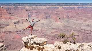 A visitor poses at the Grand Canyon, a popular US tourist spot 