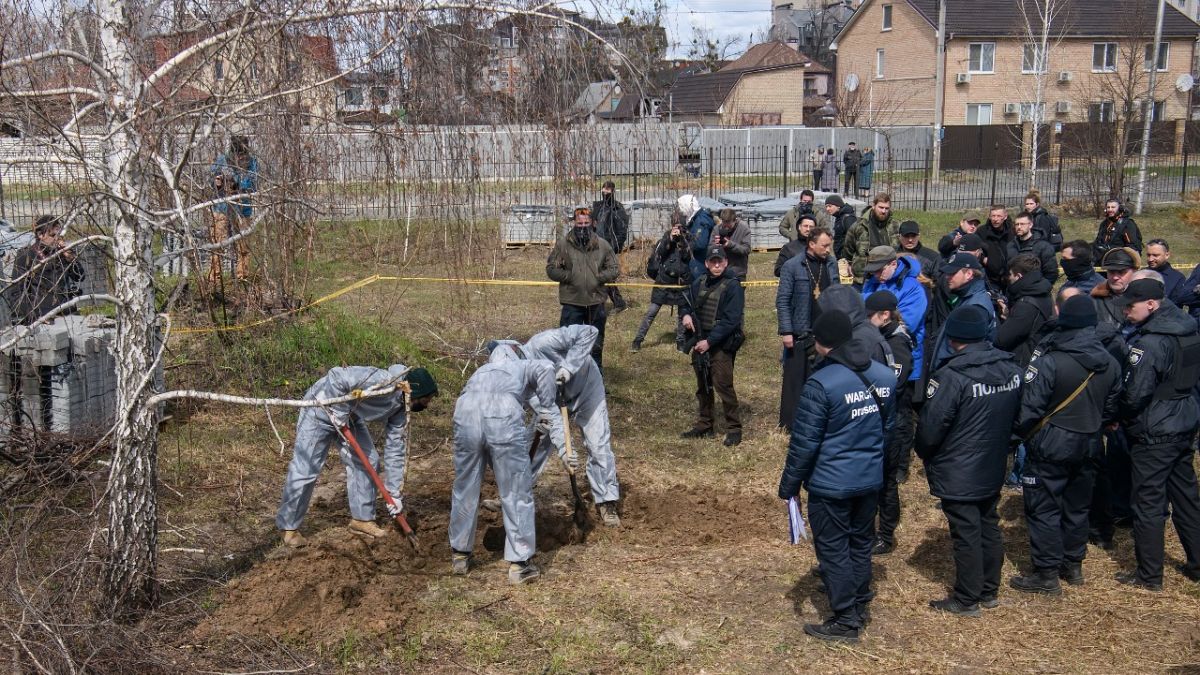 French forensics investigators, in Ukraine to investigate war crimes amid Russia's invasion, stand next to a mass grave in Bucha, near Kyiv, Ukraine, April 12, 2022.