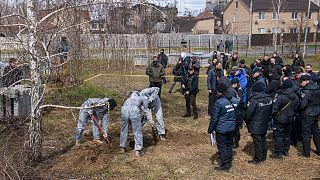 French forensics investigators, in Ukraine to investigate war crimes amid Russia's invasion, stand next to a mass grave in Bucha, near Kyiv, Ukraine, April 12, 2022.