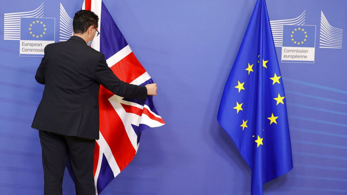 A member of staff adjusts the EU and Union flag prior to an official greeting between the EU and UK, Monday, Feb. 21, 2022. 