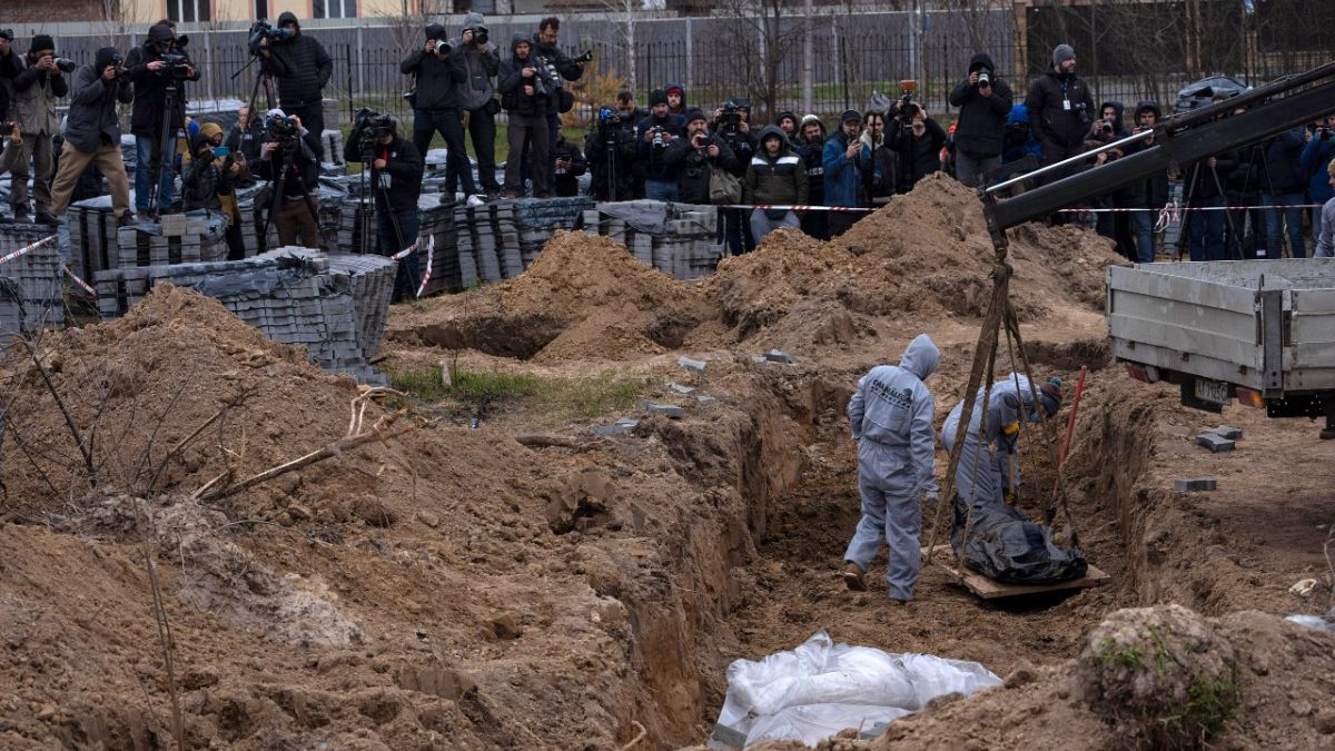 Cemetery workers exhume the corpse of a civilian killed in Bucha from a mass grave, in the outskirts of Kyiv, Ukraine, Wednesday, April 13, 2022.