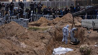 Cemetery workers exhume the corpse of a civilian killed in Bucha from a mass grave, in the outskirts of Kyiv, Ukraine, Wednesday, April 13, 2022.