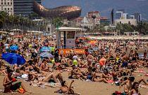 People sunbathe on a beach in Barcelona, Spain.