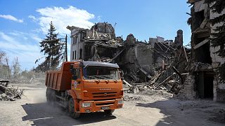 Teherautó halad el az orosz támadásokban megrongálódott színház mellett Mariupolban