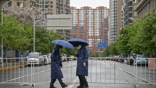 رجلان من الأمن أمام مجمع سكني مغلق في بكين