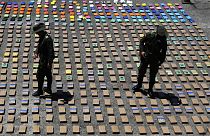 In this Thursday, 10 August 2017 file photo, police officers walk among packages of seized cocaine at the Pacific port of Buenaventura, Colombia