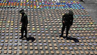In this Thursday, 10 August 2017 file photo, police officers walk among packages of seized cocaine at the Pacific port of Buenaventura, Colombia