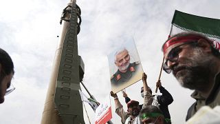متظاهرون في طهران بمناسبة "يوم القدس" يقفون قرب صاروخ "شهاب3"