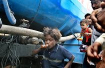 Un niño bebe agua de un camión cisterna, mientras otros esperan para beber en Nueva Delhi, India. (Archivo).