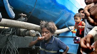 Un niño bebe agua de un camión cisterna, mientras otros esperan para beber en Nueva Delhi, India. (Archivo).