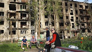 Местные жители на фоне разрушенного дома в Мариуполе, 29 апреля 2022 г.