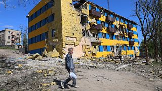 A local resident walks past a destroyed building in Mariupol, in territory under the government of the Donetsk People's Republic, eastern Ukraine, Friday, April 29, 2022.