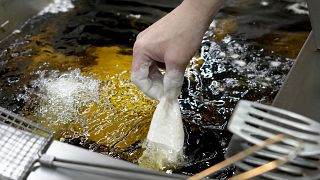 Рыбу в кляре бросают в горячее подсолнечное масло для приготовления фиш-энд-чипс, Лондон