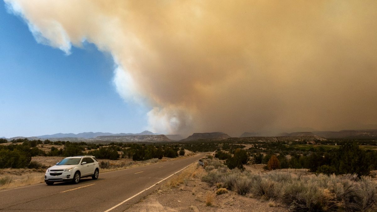 A vehicle heads away from a plume of smoke from the Cerro Pelado Fire burning in the Jemez Mountains on Friday, April 29, 2022 in Cochiti, New Mexico, US.