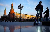 FILE - Youth ride scooters in Manezhnaya Square near Red Square and the Kremlin after sunset in Moscow, Russia, on April 20, 2022