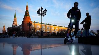 FILE - Youth ride scooters in Manezhnaya Square near Red Square and the Kremlin after sunset in Moscow, Russia, on April 20, 2022