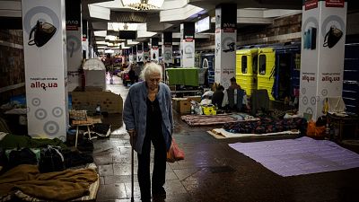 An elderly woman walks as she takes shelter and lives in an underground metro station in Kharkiv.