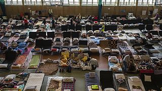 FILE - People who fled the war in Ukraine rest inside an indoor sports stadium being used as a refugee center, in Medyka, a border crossing between Poland and Ukraine