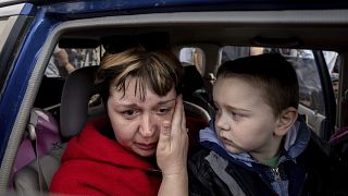 Natalia Pototska, 43, cries as her grandson Matviy looks on in a car at a center for displaced people in Zaporizhzhia, Ukraine, Monday, May 2, 2022.