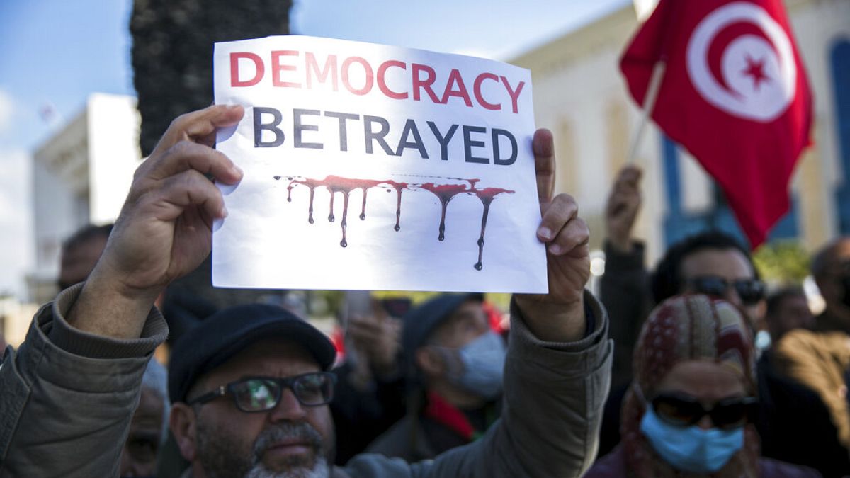 متظاهر يرفع لافتة كتب عليها "خيانة الديمقراطية" خلال مظاهرة ضد الرئيس التونسي قيس سعيد في تونس العاصمة، الأحد 13 فبراير 2022