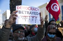 متظاهر يرفع لافتة خلال مظاهرة ضد الرئيس التونسي قيس سعيد في تونس العاصمة، الأحد 13 فبراير 2022