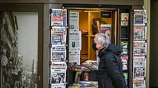 A passer-by in front of a newspaper kiosk in December 2021 in Athens, Greece