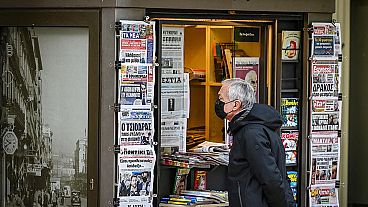 A passer-by in front of a newspaper kiosk in December 2021 in Athens, Greece