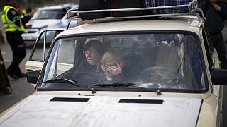 People wait in a car to be processed upon their arrival at a reception center for displaced people in Zaporizhzhia, Ukraine, Monday, May 2, 2022.