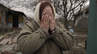 Женщина плачет у ворот своего разрушенного дома в Андреевке, 6 апреля 2022.