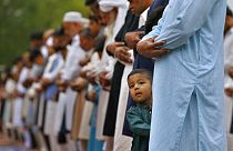 طفل يقف بجانب والده وهو يؤدي صلاة عيد الفطر بمناسبة انتهاء شهر رمضان في روالبندي، باكستان، الثلاثاء 3 مايو 2022