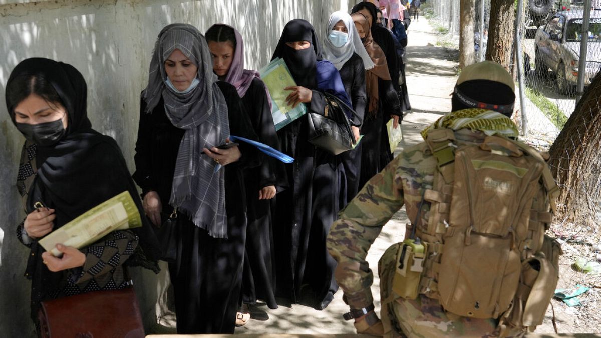 Un taliban monte la garde pendant que des femmes font la queue devant le bureau des passeports à Kaboul