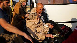 Idős nőt emelnek le az egyik buszról, mely Zaporzzsjába érkezett a mariupoli evakuáltakkal