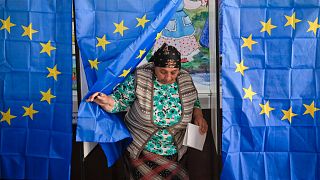 A woman exits a voting cabin with curtains depicting the European Union in Baleni, Romania, May 26, 2019.
