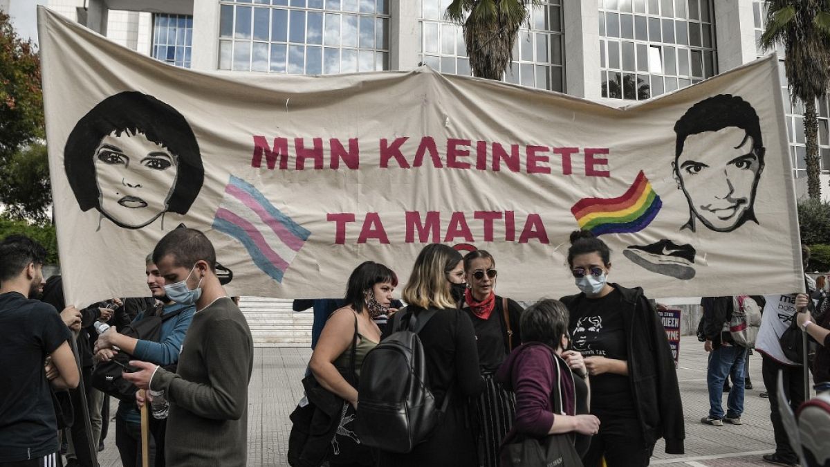 Activists hold a banner reading "Don't close your eyes" outside the court in Athens.