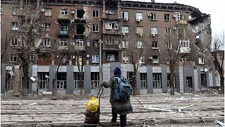 رجل ينظر إلى مبنى سكني متضرر بالقرب من Illich Iron & Steel Works Metallurgical Plant ثاني أكبر مشروع تعدين في أوكرانيا