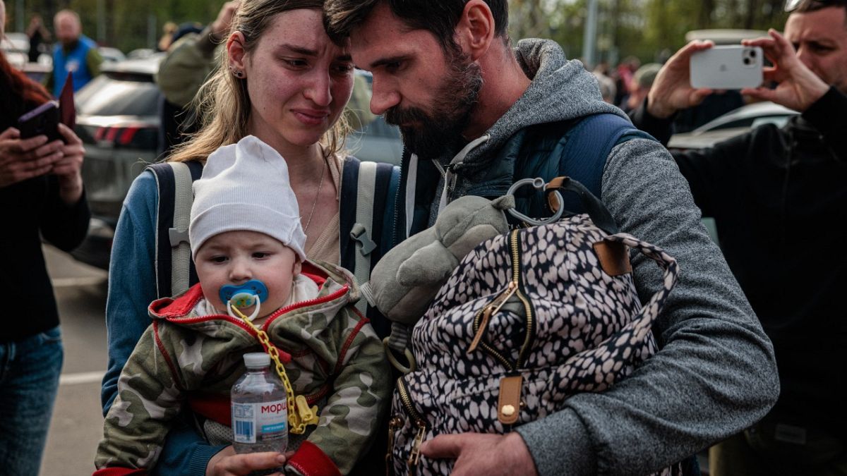 A man welcomes Anna Zaitseva and her son Svyatoslav, 6 month old, after arriving from Mariupol at a reception centre in Zaporizhzhia on May 3, 2022. 