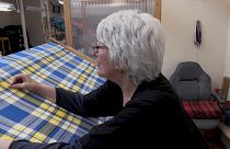 Eine Weberin im schottischen Keith arbeitet am gelb-blauen Stoff