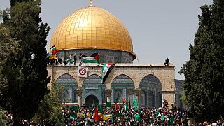 فلسطينيون يلوحون بالأعلام الفلسطينية في مجمع المسجد الأقصى بالقدس. 2022/04/29