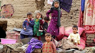 أطفال متضررون من الفيضانات يجلسون خارج منزلهم المدمر في منطقة قادس في محافظة بادغيس في أفغانستان 4 مايو 2022.