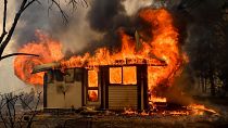 Flames from the Morton Fire consume a home near Bundanoon, Australia in 2020. 