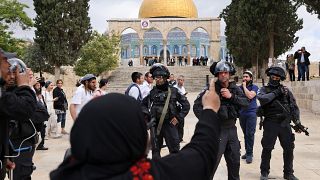 امرأة فلسطينية أمام الشرطة الإسرائيلية التي ترافق مجموعة من الزوار اليهود أمام مسجد قبة الصخرة في مجمع المسجد الأقصى في البلدة القديمة في القدس، الخميس 5 مايو 2022
