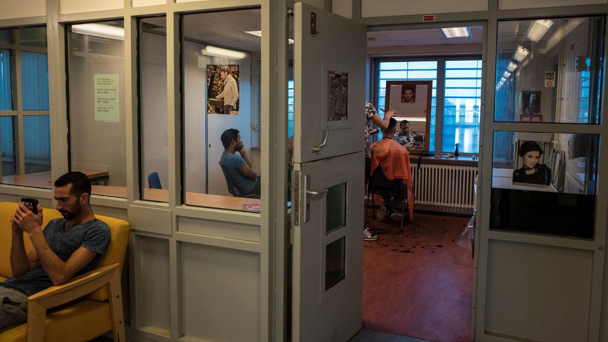 پناهجویان ایرانی در حال اصلاح موی سر یکدیگر در اردوگاه پناهندگان در هلند