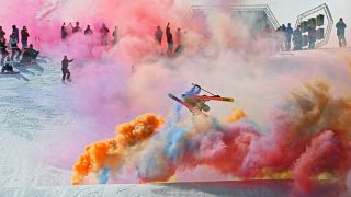 A freeskier mid-air above a jump surrounded by colour