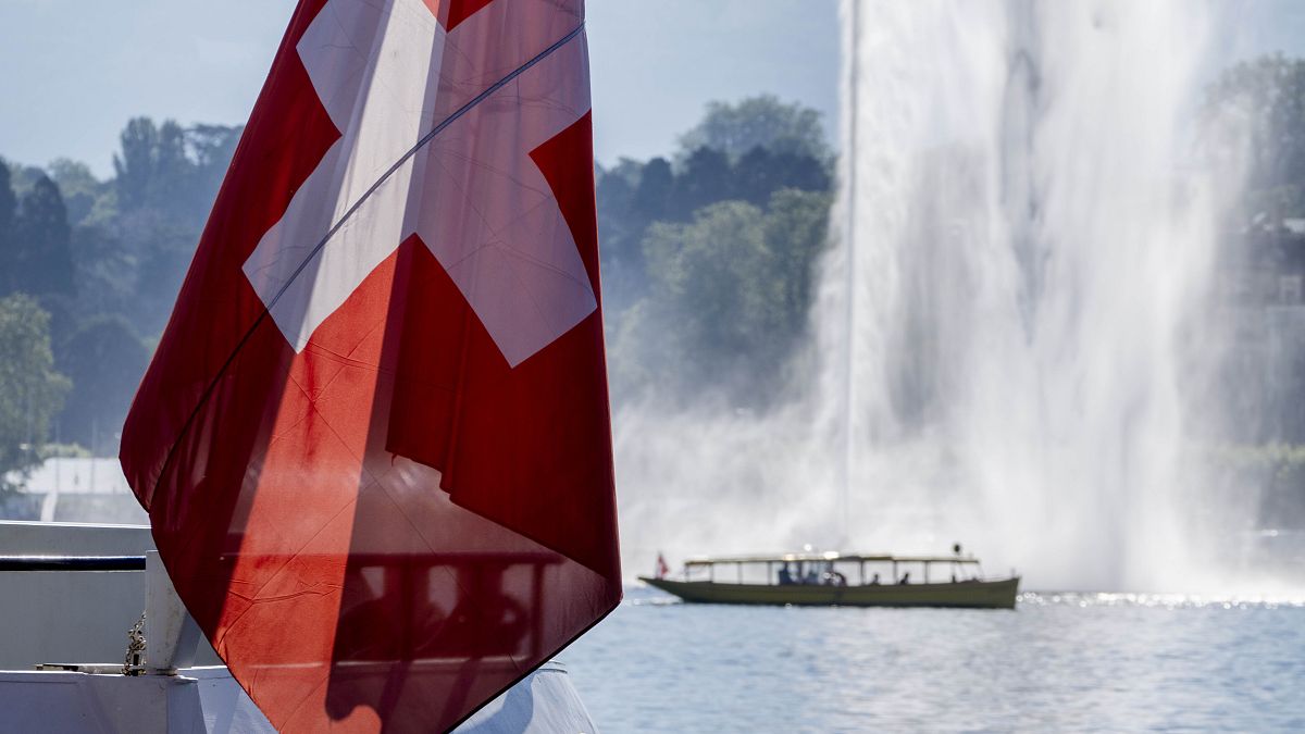 Швейцарский флаг на фоне фонтана в Женевском озере