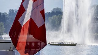 Швейцарский флаг на фоне фонтана в Женевском озере